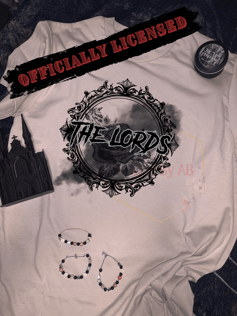Cream The Lords tee with an ornate rose frame, styled with a cathedral figurine, The Vow Ceremony candle, and I vow you vow we vow bracelets