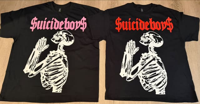 Two black Suicide Boyz concert tees with a praying skeleton — pink or red lettering