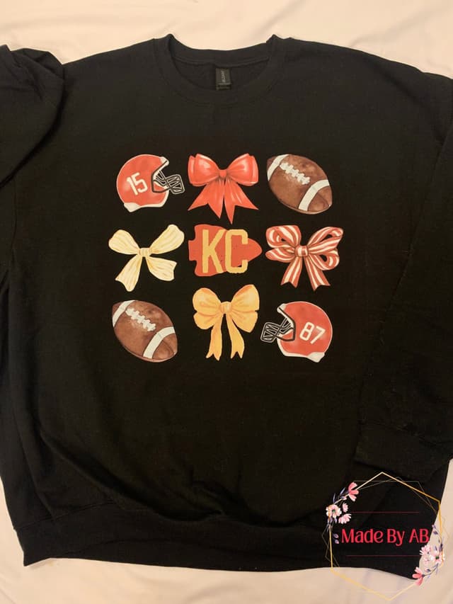 Black KC sweatshirt with watercolor bows, footballs, and helmets 15 and 87